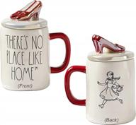 wizard of oz-inspired mug with "there's no place like home" quote and ruby-red-slipper top by rae dunn logo