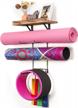 wall-mounted yoga mat holder with wood shelves and hooks for storage of exercise mats, foam rollers, and resistance bands at home gym and fitness classes logo