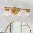 gold vanity light with 3 clear globe glass for bathroom, 19.5” (l) x6” (w) x 7.5” (h) by ruziniu logo